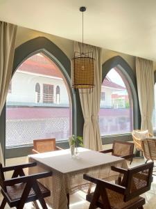 a dining room with a table and two arched windows at The Vientiane Capitol "Capitol Residence" in Vientiane