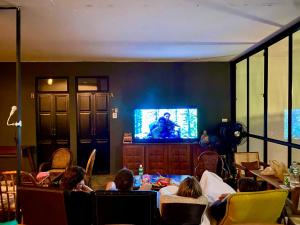 a group of people sitting in chairs watching a television at D Hostel by the river in Kanchanaburi City