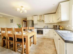a kitchen with white cabinets and a wooden table and chairs at 3 Bed in Poulton-le-fylde oc-41764 in Preesall