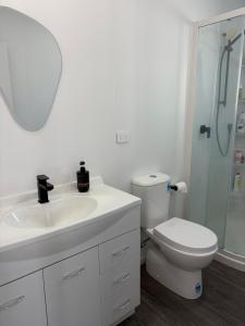 a bathroom with a sink and a toilet and a mirror at Whangamata Bach Life in Whangamata +11 photos