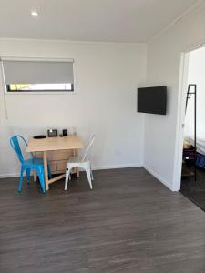 a room with a table and two chairs and a television at Whangamata Bach Life in Whangamata
