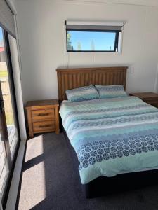a bedroom with a bed and a window at Whangamata Bach Life in Whangamata