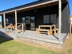 a house with a wooden deck with two benches on it at Whangamata Bach Life in Whangamata