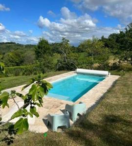 a swimming pool with two white chairs next to it at Maison du causit in Aubertin