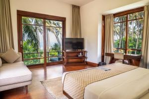 a bedroom with a bed and a tv and windows at The Villa by Contemporary Ceylon in Wadduwa