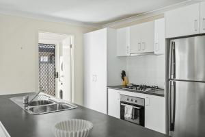 a kitchen with white cabinets and a stainless steel refrigerator at Comfortable 4BR Coomer Escape Close to Everything in Gold Coast