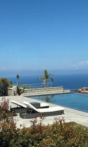 a swimming pool with two lounge chairs and the ocean at Luxury Villa in Calabria in Gasponi