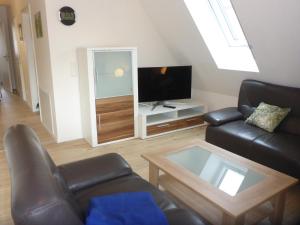 a living room with a leather couch and a tv at Herrmanns-Ferienhaus Steigerwald in Schlüsselfeld