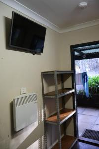 a room with a tv on the wall and a book shelf at Normalee manor hostel in Deanmill