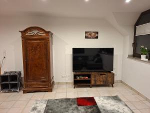 a living room with a television and a large wooden cabinet at Ferienwohnung im Grünen in Korschenbroich