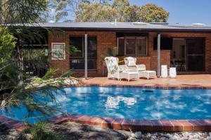 a swimming pool with two chairs and a house at The Pool House in Rosebud +40 photos