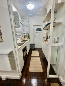 a small kitchen with white cabinets and a rug at Pet Friendly Acer Arena Accommodation in Sydney