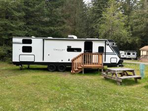 a white rv parked in a field with a wooden deck at The Bunkhouse Camper in Klamath +12 photos