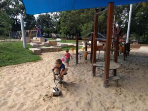 a young boy playing with a scooter in the sand at a playground at Pet Friendly Acer Arena Accommodation in Sydney +5 photos