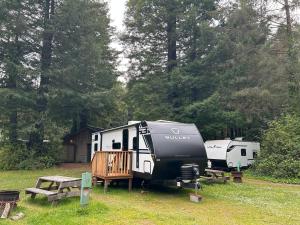 a camp site with two rvs and a picnic table at The Bunkhouse Camper in Klamath