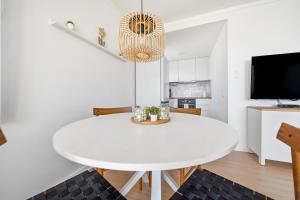 a white dining room with a white table and a tv at Vista Roses Mar - Ariadna in Roses