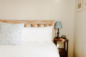 a bed with white sheets and a lamp on a table at Paradise Creek Cottage in Moscow