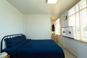 a bedroom with a blue bed and a tv at Uncle NID Hostel in Lat Krabang