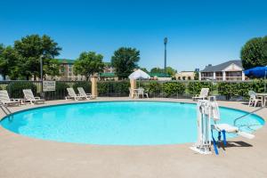 una gran piscina con tumbonas y mesas. en Baymont by Wyndham Clarksville Northeast, en Clarksville