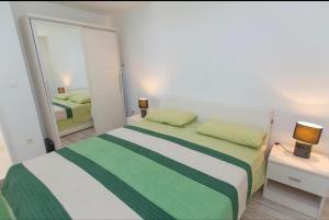 a bedroom with a green and white bed and a mirror at Apartman Nick in Mlini