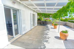an outdoor patio with awning and plants on a house at Apartman Nick in Mlini