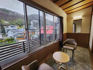 a room with two chairs and a window with a view at Snow Monkey Lodge in Yamanouchi
