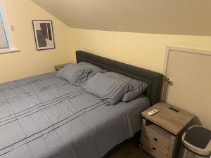 a bed with blue pillows and a night stand next to it at Cute as HECK! in Tacoma