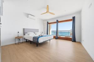 a white bedroom with a bed and a large window at Vista Roses Mar - El Brancs in Roses +27 photos