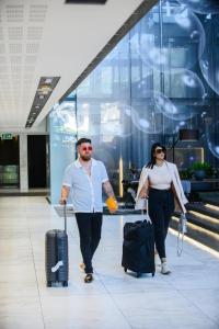 Ein Mann und eine Frau gehen mit Gepäck durch einen Flughafen in der Unterkunft The Capital 15 on Orange Hotel & Spa in Kapstadt + 127 Fotos