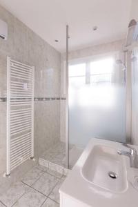 a white bathroom with a shower and a sink at Appartements - Chez Alice in Salies-de-Béarn +10 photos