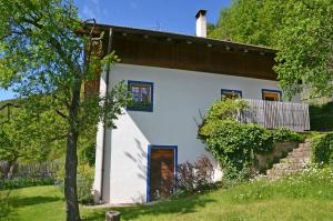 a white house with blue windows and a tree at Kohlstatt Hof Ferienhaus in Verano