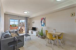 a living room with a couch and a table and chairs at Apartamento Duque Beach in Adeje