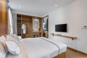 a bedroom with a white bed and a television at 鹿野山房 DeerHoliday Inn in Dali