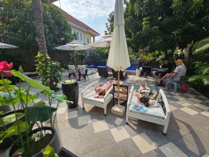 two people laying in beds on a patio with an umbrella at Angkor Rise Residence in Siem Reap