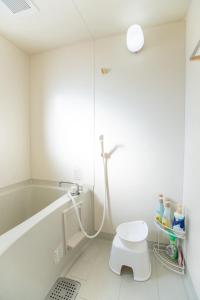 a white bathroom with a shower and a toilet at Nagano Station Inn East in Nagano