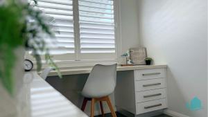 a white desk with a chair next to a window at Beachside Oasis in Caves Beach +17 photos