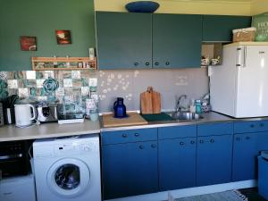 a kitchen with blue cabinets and a washing machine at Tinyhouse CARPE DIEM in Dirkshorn