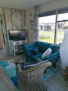 a living room with a blue couch and a tv at Tinyhouse CARPE DIEM in Dirkshorn