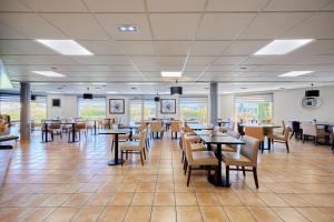 a dining room with tables and chairs and windows at CIT'HOTEL Armony Hotel in Bourg-Achard