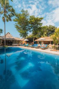 a large swimming pool with palm trees and umbrellas at Lay Day Gili T in Gili Trawangan