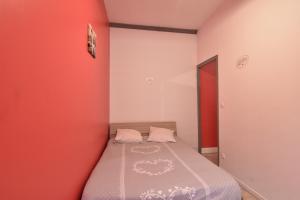 a small bedroom with a bed in a red wall at Sweet garden in La Fère
