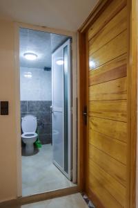 a bathroom with a toilet and a wooden door at The Palm Surfhouse in Tamraght Ouzdar