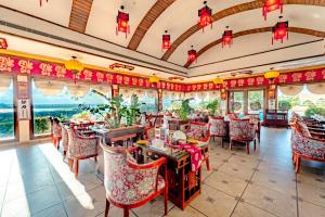 a restaurant with red chairs and tables and windows at Noor-Us-Sabah Palace in Bhopal