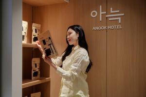 a woman standing in a room holding a box at Anook Hotel Suwon Ingye 2 in Suwon