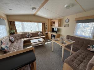 a living room with a couch and a table at Sunnymede i15 Hot Tub - pet friendly, bed linen - Meadow Lakes Caravan & Lodge Hire in Ingoldmells