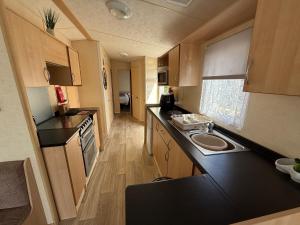 a small kitchen with a black counter top in a caravan at Sunnymede i15 Hot Tub - pet friendly, bed linen - Meadow Lakes Caravan & Lodge Hire in Ingoldmells