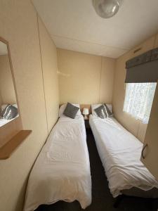 two beds in a small room withermottermottermott at Sunnymede i15 Hot Tub - pet friendly, bed linen - Meadow Lakes Caravan & Lodge Hire in Ingoldmells +7 photos