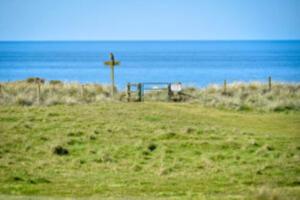 a cross on the side of a field near the ocean at Rhiw in Llangian