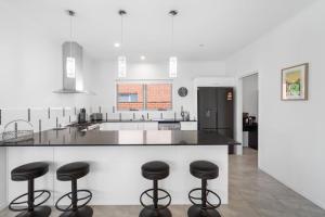 a kitchen with black stools at a counter at 1 Seaspray Avenue in Coolum Beach