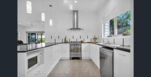 a large white kitchen with white cabinets and stainless steel appliances at 1 Seaspray Avenue in Coolum Beach +14 photos